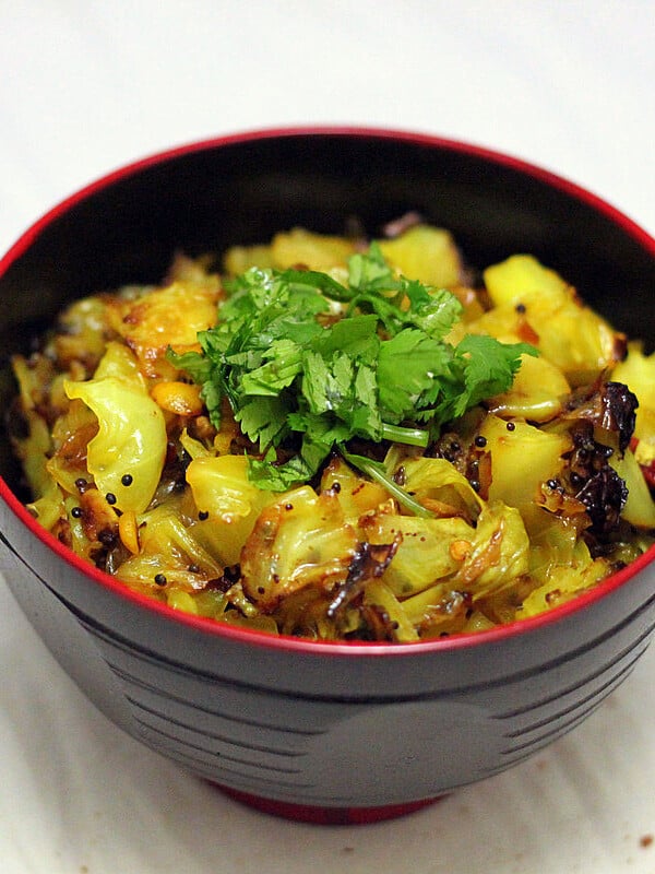 A dark bowl of patta gobi sabzi on a marble countertop