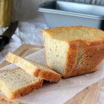 A loaf of gluten free vegan white bread on parchment paper and a cutting board