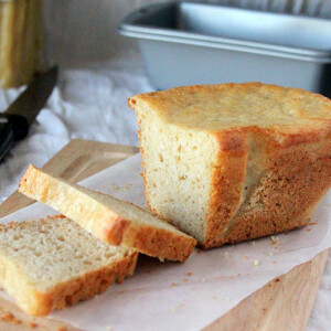 A loaf of gluten free vegan white bread on parchment paper and a cutting board