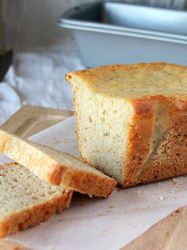 A loaf of gluten free vegan white bread on parchment paper and a cutting board