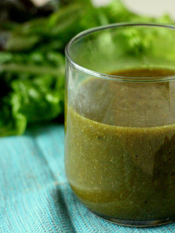 A green smoothie in a short glass, on a light blue background