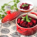 A small red pot on a blue pattern fabric, containing a beet and carrot salad