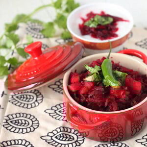 A small red pot on a blue pattern fabric, containing a beet and carrot salad