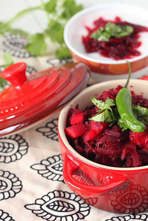 A small red pot on a blue pattern fabric, containing a beet and carrot salad