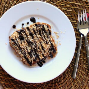 A slice of french toast on a white plate, drizzled with chocolate