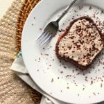 A slice of French toast on a white plate with a fork. Sprinkled with cocoa powder