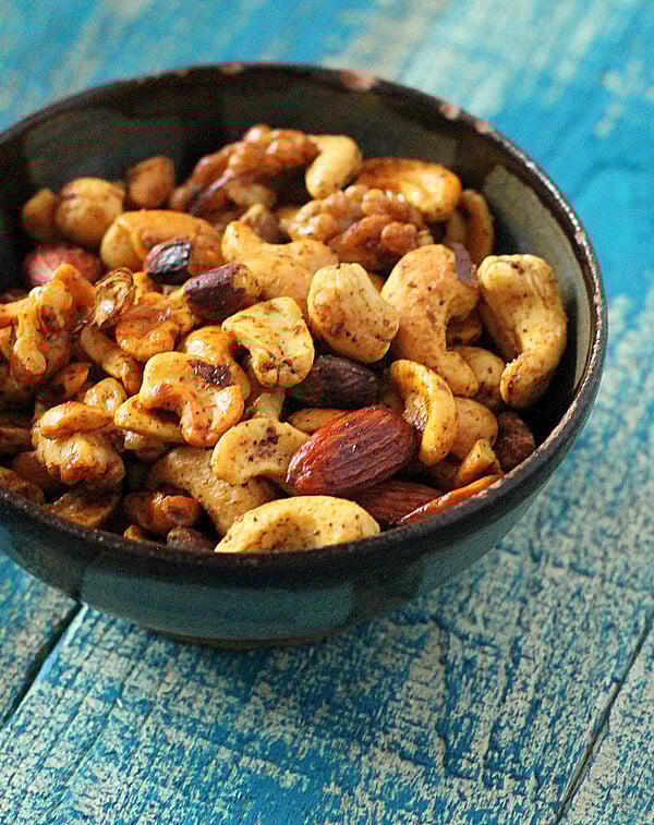 A bowl of spiced roasted nuts on a blue wood background