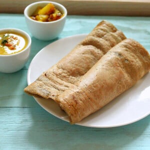 A folded dosa on a white plate on a blue wooden background