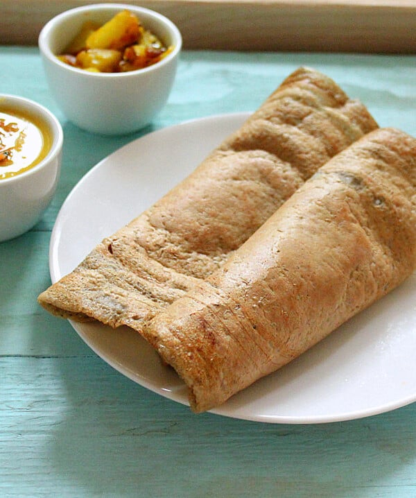 A folded dosa on a white plate on a blue wooden background