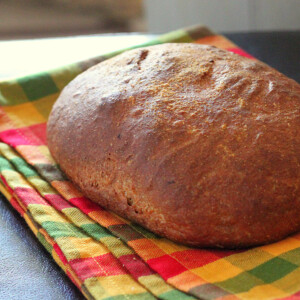 A loaf of faux sourdough bread on an orange and green gingham fabric
