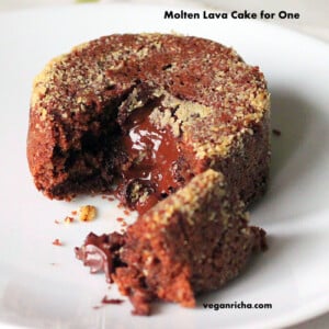 A molten lava cake on a white plate. A piece is broken away to show the melted chocolate centre