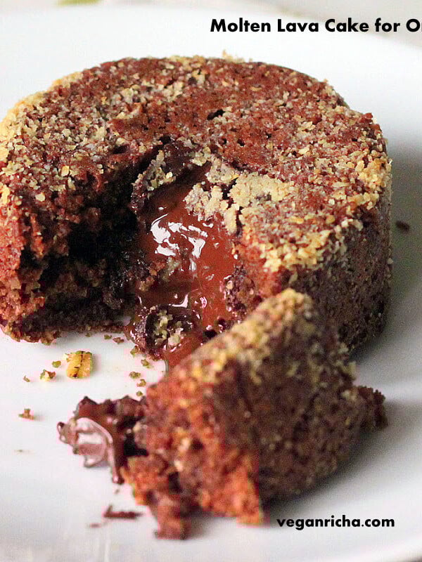 A molten lava cake on a white plate. A piece is broken away to show the melted chocolate centre