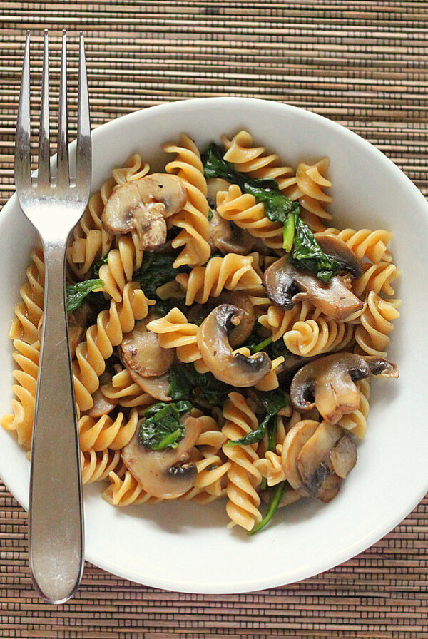 Mushroom fusilli in a white bowl with a fork. On a bamboo mat