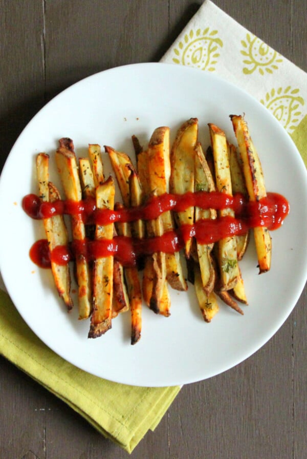 A plate of baked French fries with tomato sauce