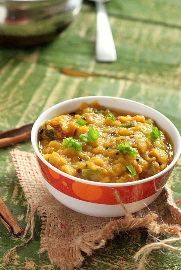 A bowl of red lentil stew on a green background