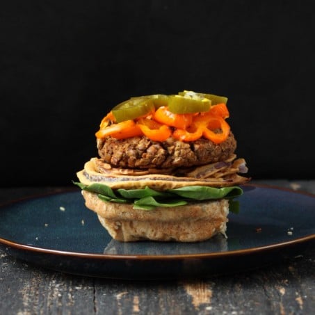 loaded vegan lentil burger without the bun top on a blue plate