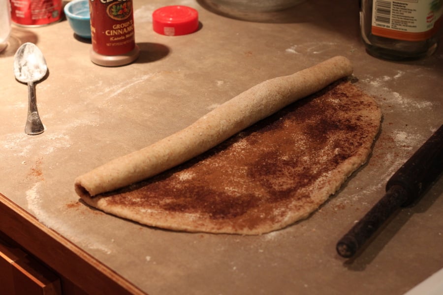 vegan cinnamon rolls  cinnamon filled dough rectangle being rolled into a roll to make vegan cinnabons