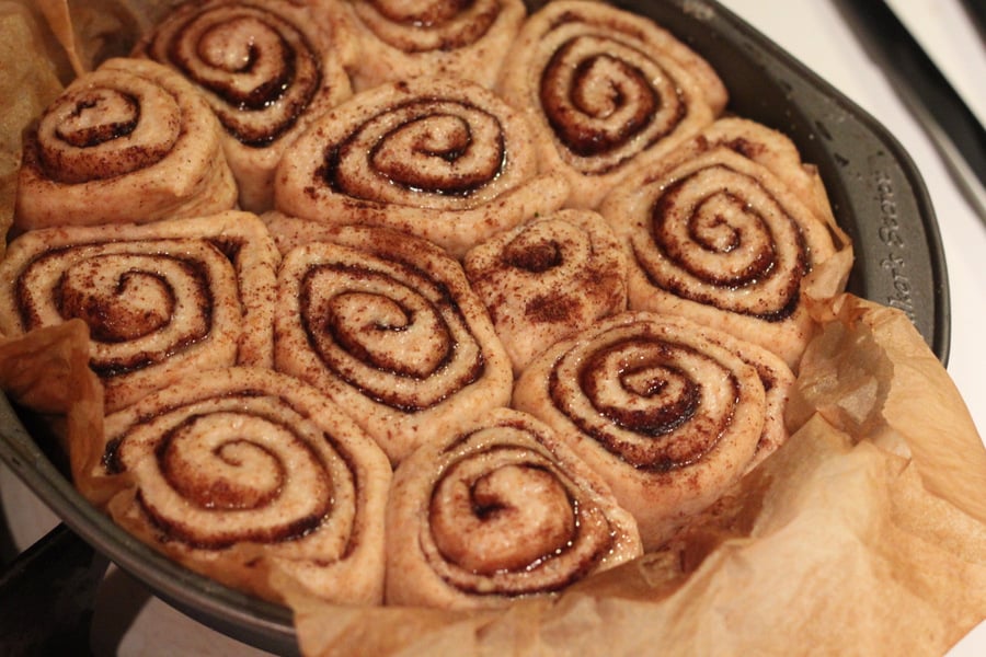 vegan cinnamon rolls  risen vegan cinnamon buns in a round cake pan ready to be baked