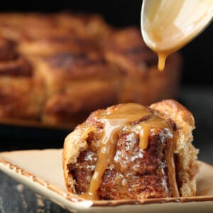 maple glaze being drizzled on top of a homemade vegan cinnamon roll