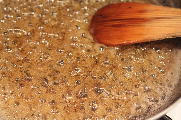 salted caramel brownies vegan coconut caramel sauce being stirred in a sauce pan with a wooden spoon