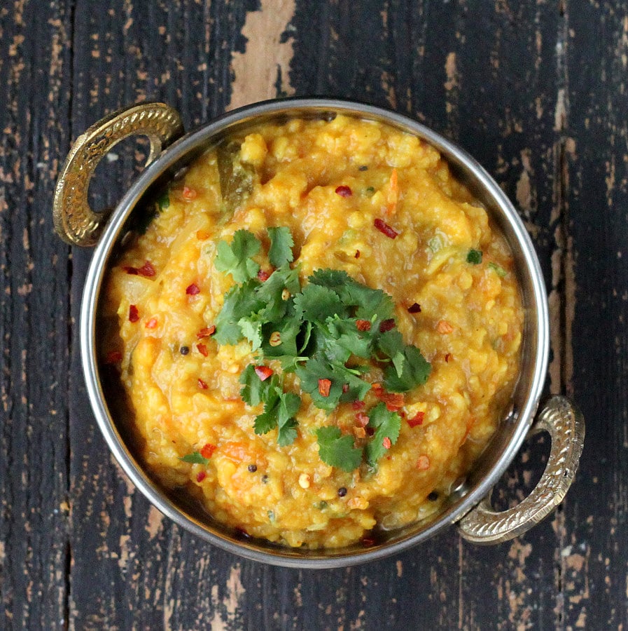 mung dal overhead shot of a bowl of Mung Dal (Moong Dal) and Split Pigeon Pea Stew topped with crushed red pepper and chopped herbs