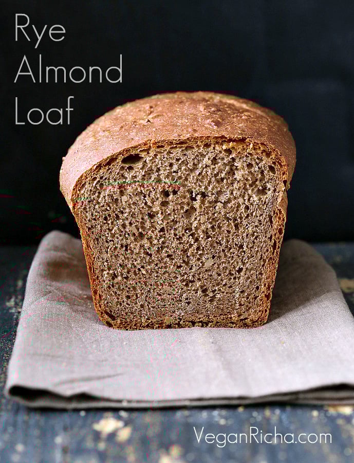 vegan burger buns  a sliced-open loaf of whole wheat rye and almond flour sandwich bread on a light brown kitchen towel