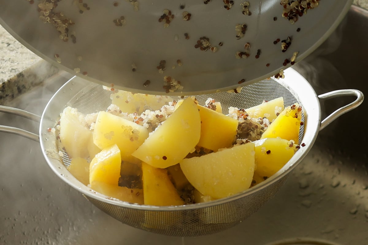 adding potatoes and quinoa to the bowl