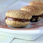 three tiramisu cookies on a white plate, dusted with cocoa powder