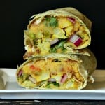 a stacked red lentil hummus wrap against a black background