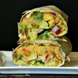 a stacked red lentil hummus wrap against a black background