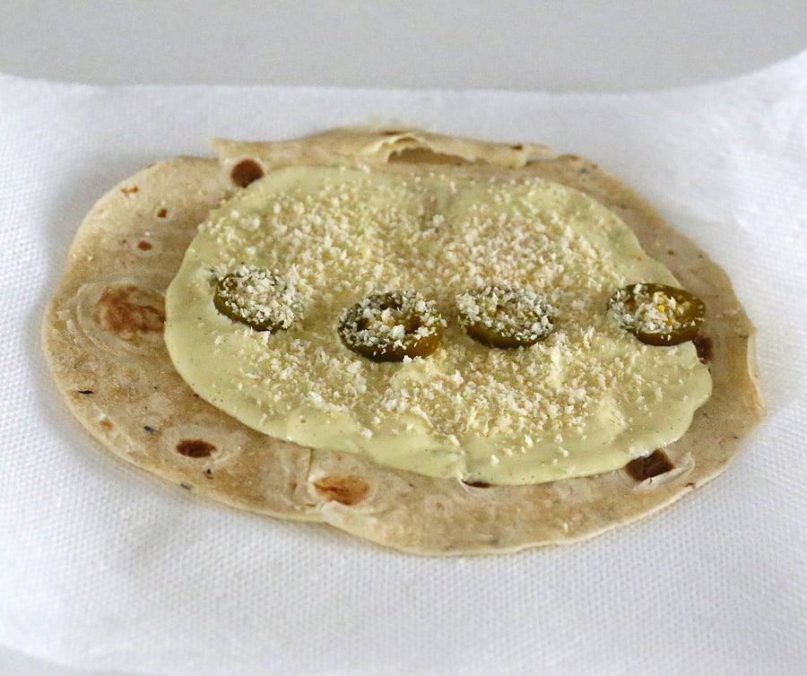 tempeh scramble  cashew jalapeno popper dip being spread on a wheat tortilla to make vegan breakfast wrap