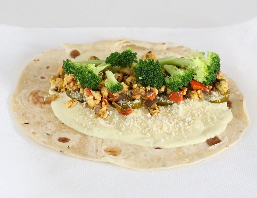 tempeh scramble  a wrap topped with cashew cream, tempeh scramble and veggies ready to be rolled