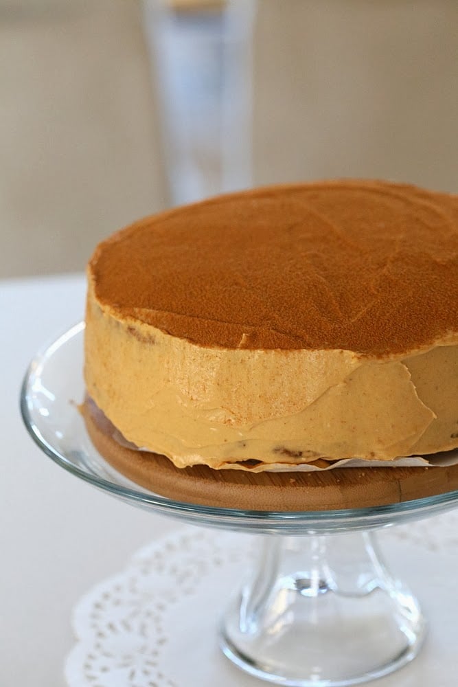 mousse cake side view of a vegan pumpkin mousse cake on a glass cake stand