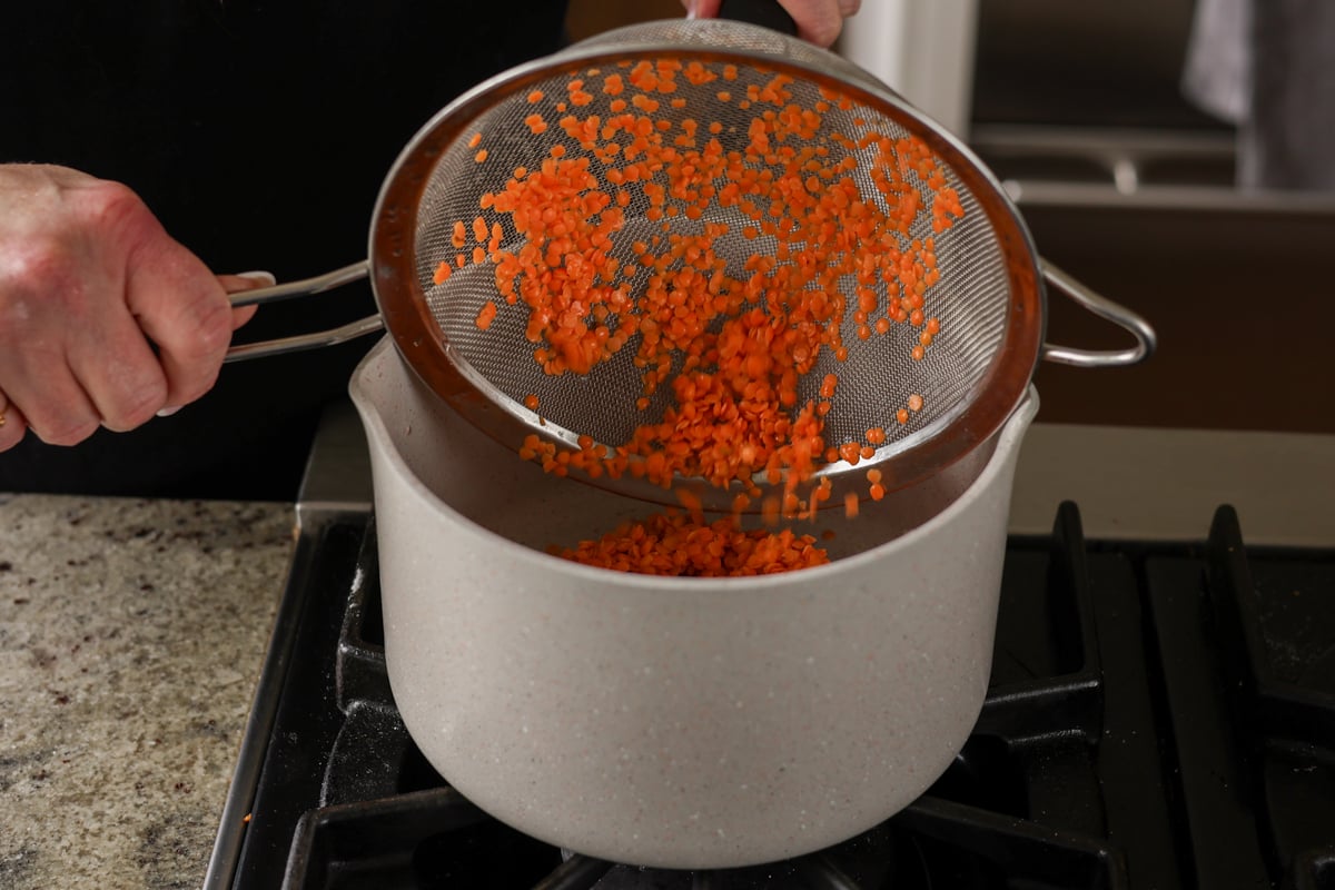 transferring rinsed lentils to the pan