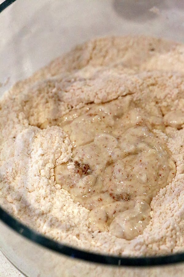 gluten free biscuits recipe  wet ingredients being added to dry ingredients in a glass bowl to make gluten free biscuits recipe
