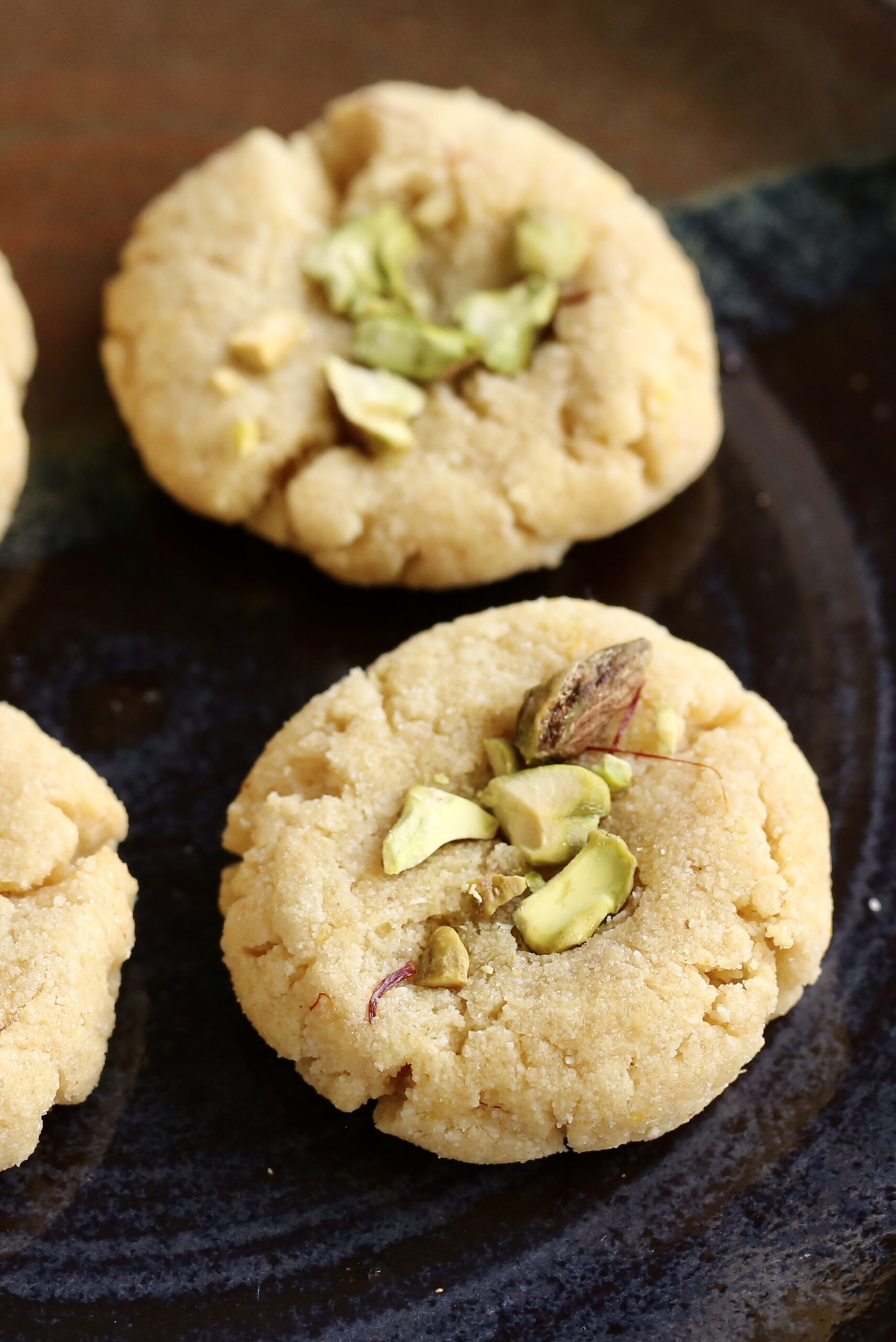 Indian kesar peda cookies on a black plate