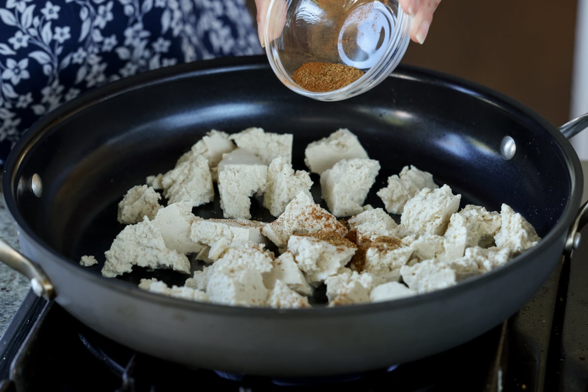 adding tofu and spices to the pan