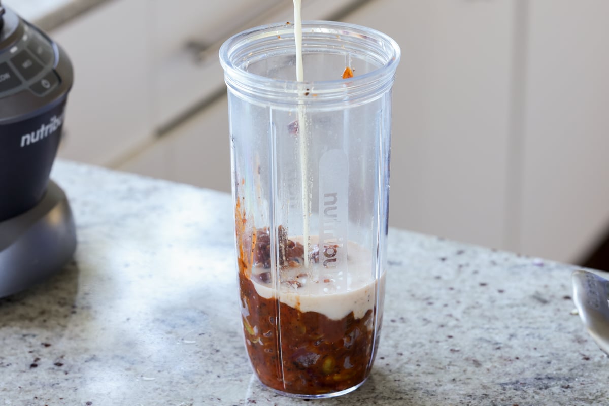adding coconut milk to the sauce mixture in the blender