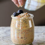 sprinkling pecans on top of carrot cake overnight oats