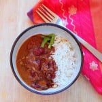 A bowl of red kidney bean curry and rice with a fork and red napkin