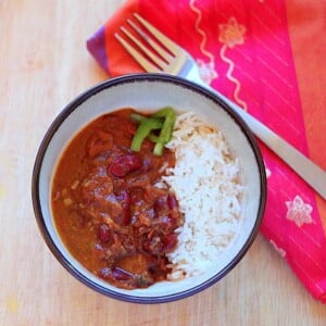 A bowl of red kidney bean curry and rice with a fork and red napkin