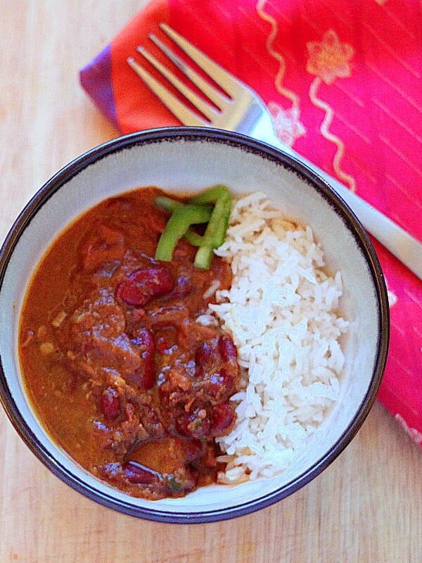 A bowl of red kidney bean curry and rice with a fork and red napkin
