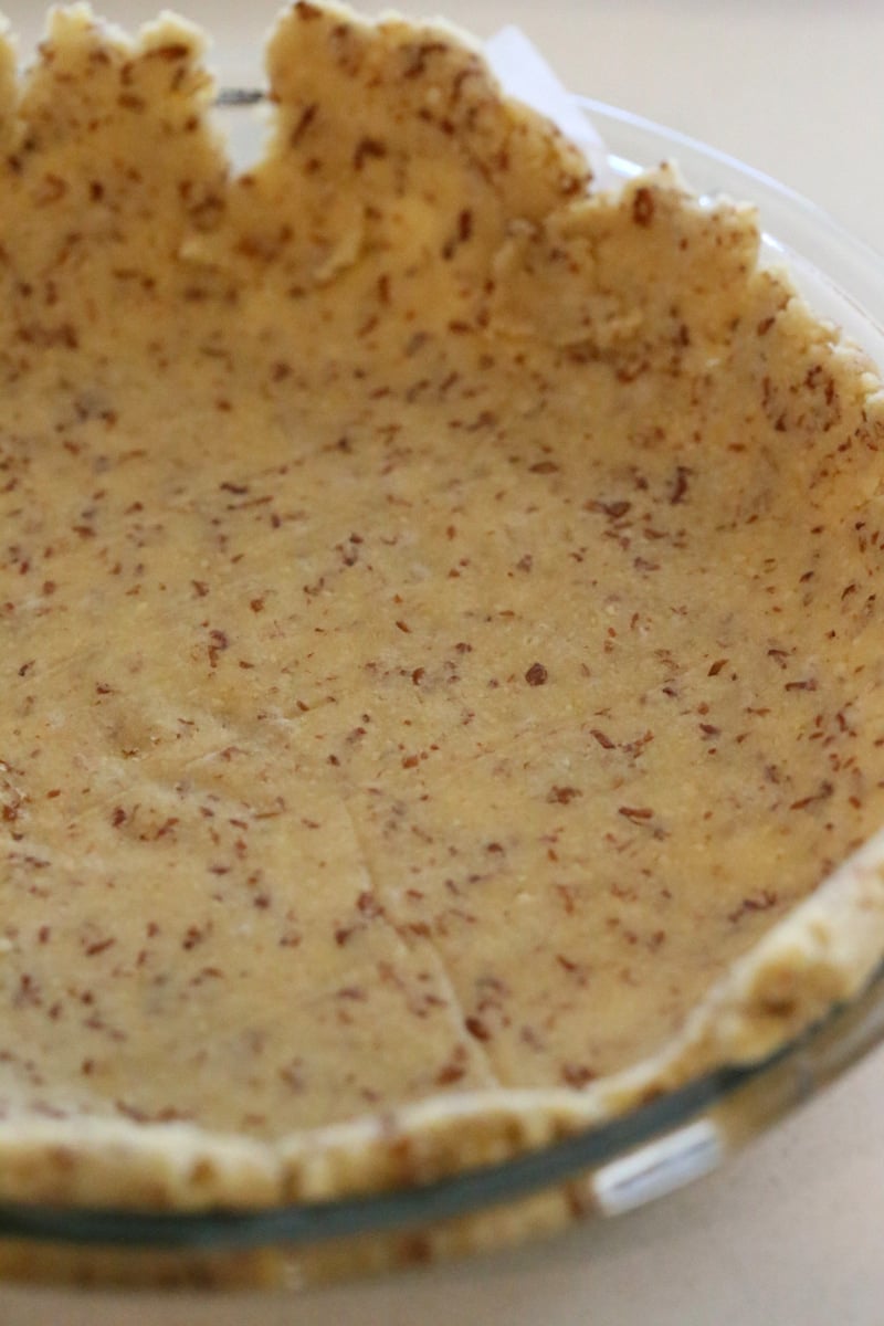 almond flour pie crust side view of a vegan gluten-free almond flour pie crust placed in a glass pie dish ready for baking