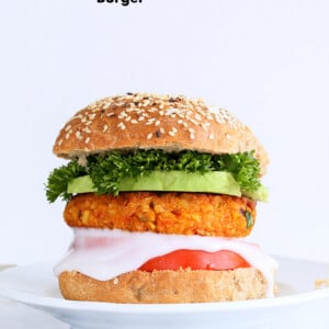 Spicy Chickpea Burger with toppings on sesame seed bun on a white plate