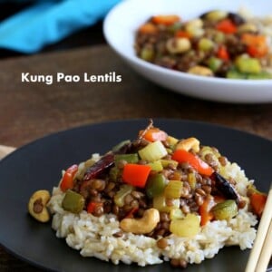 Kung Pao Lentils over brown rice on a black plate with chopsticks