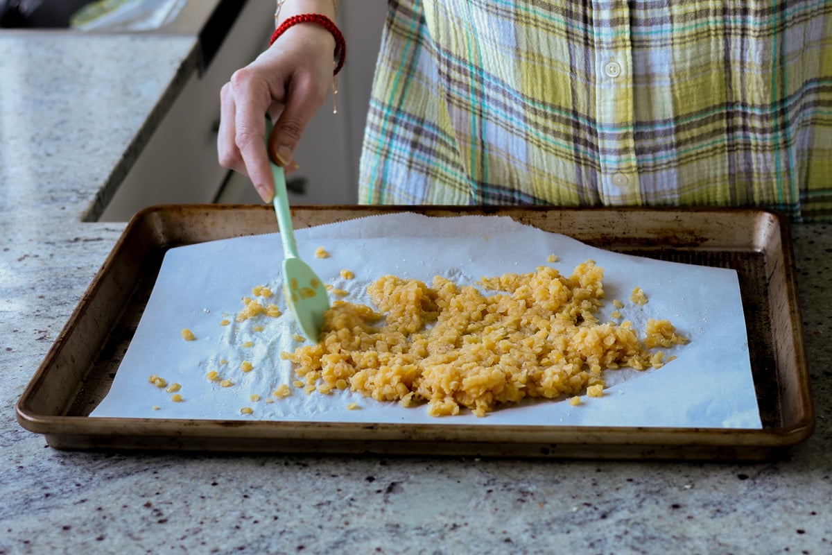 stirring red lentils on the baking pan with sugar