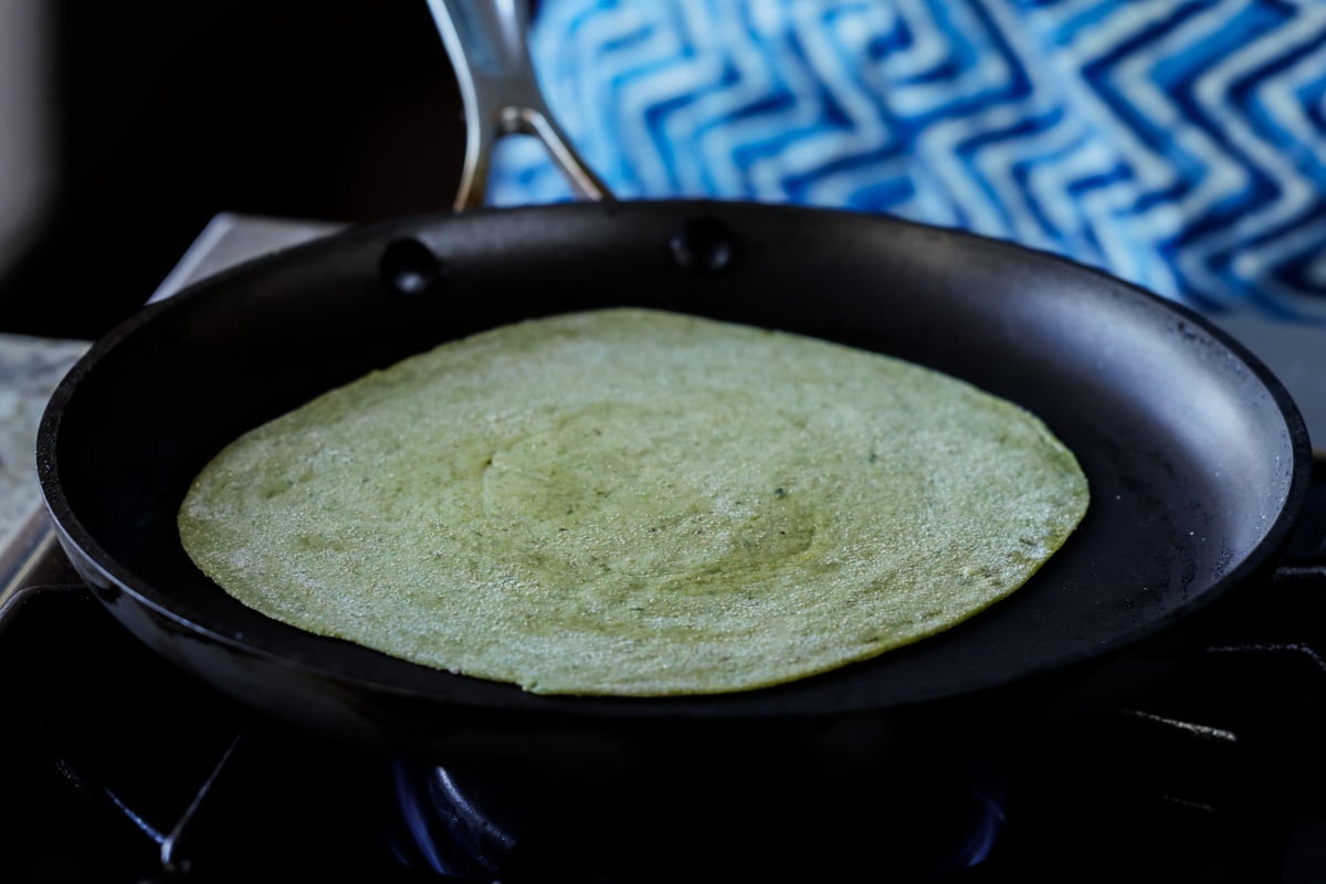 adding a spinach paratha to the pan