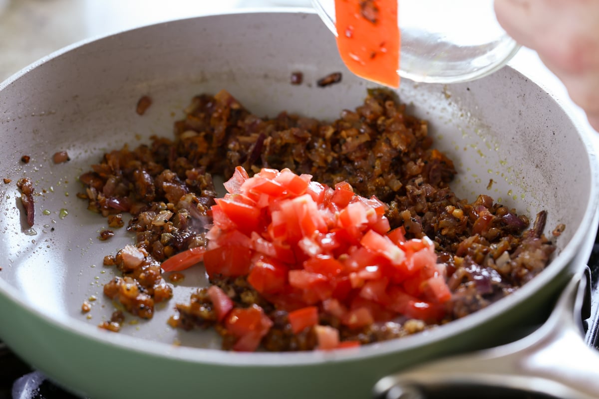 adding tomato to the pan