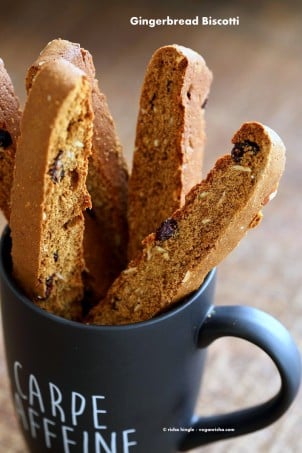 Vegan Gingerbread Biscotti with cranberries, almonds, candied ginger and gingerbread spice in a black cup