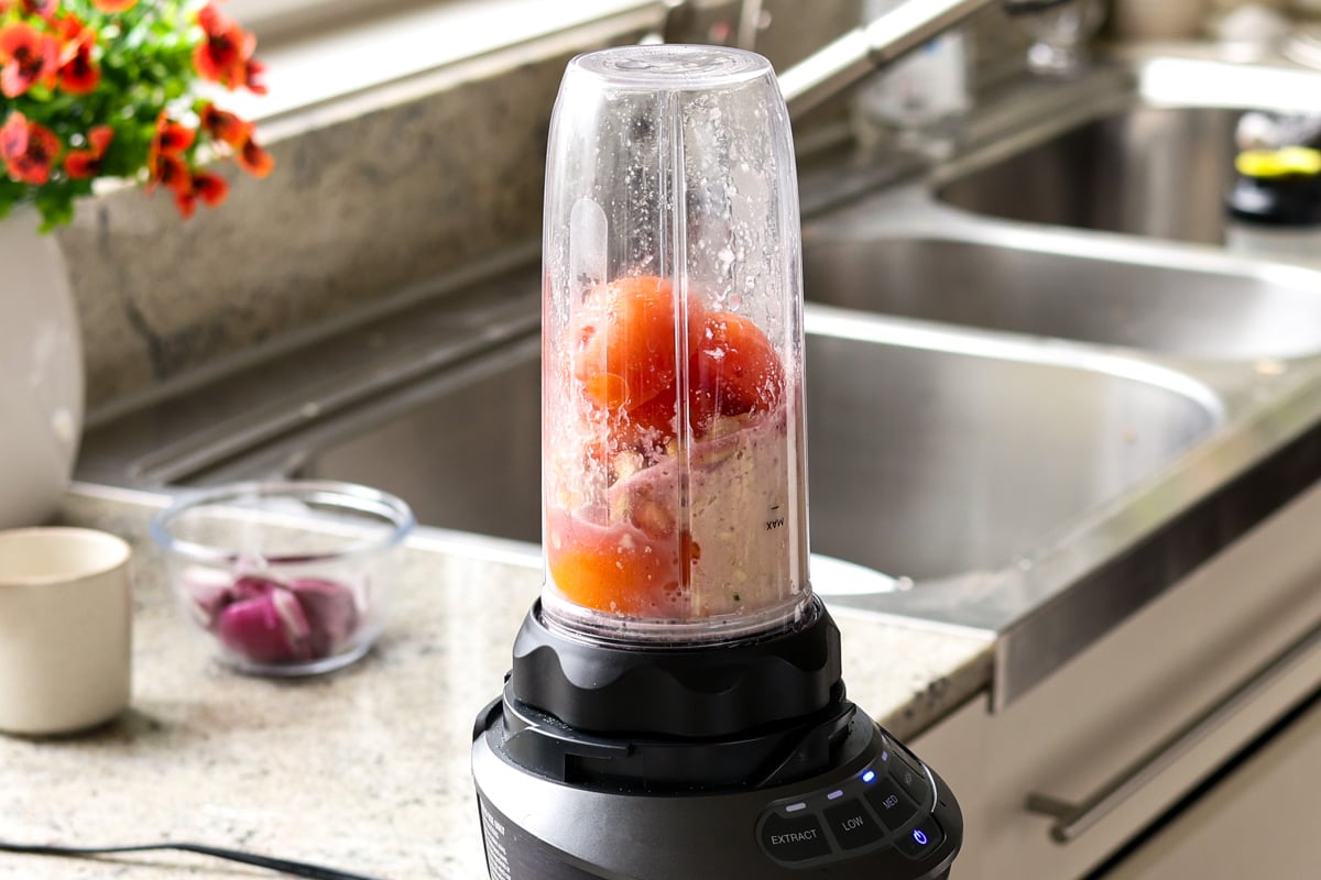 adding tomatoes, cashews, and spices to the blender